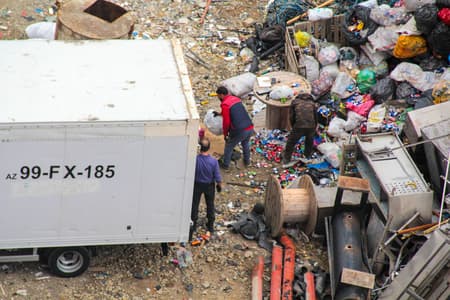 Workers sorting waste near a truck for recycling